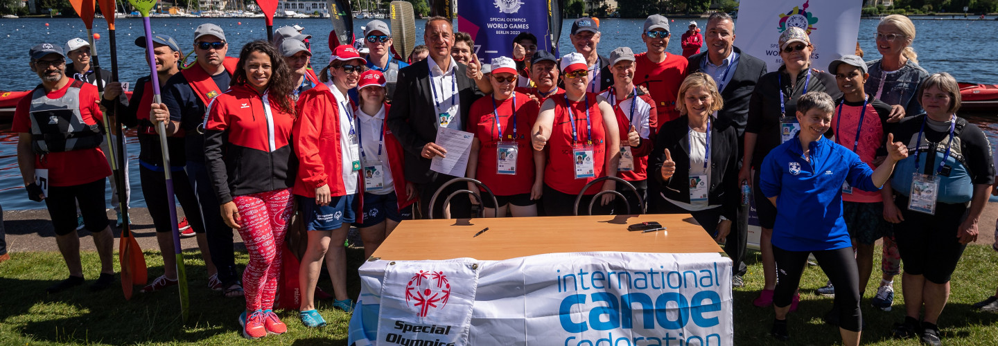 Von vielen fröhlichen Athlet*innen in Sportkleidung umgeben: Bettina Schilling (SOD / rechts), Lou Lauria (SOI /Mitte), John Edwards (ICF /
Mütze), Thomas Konietzko (ICF / links).