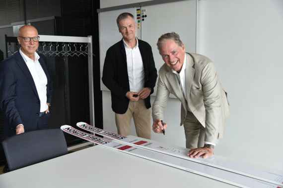 Die Zusammenarbeit zwischen Fischer Sports und Stiebel Eltron wurde stilecht auch per Unterschrift von Heinz-Werner Schmidt (rechts) und Franz Föttinger auf echten Sprungski mit Stiebel Elton-Branding besiegelt. Links Claus Kroll-Schlüter, Leiter Marketing Communication von Stiebel Eltron.